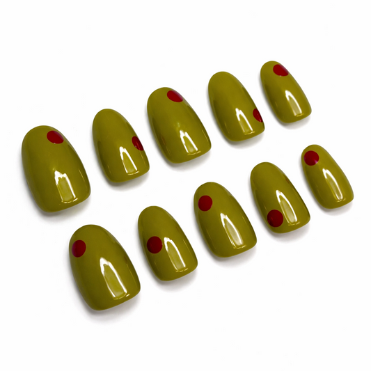 Set of green nail extensions with red dots on a white background
